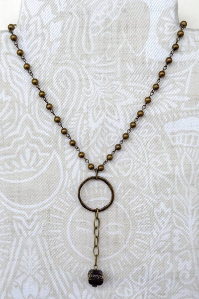 a short bronze necklace with a lobster clasp and bronze beads. at the bottom there is a lariat bronze charm.