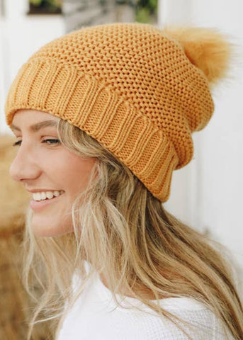  A mustard yellow knit beanie with a pom-sherpa lined hat