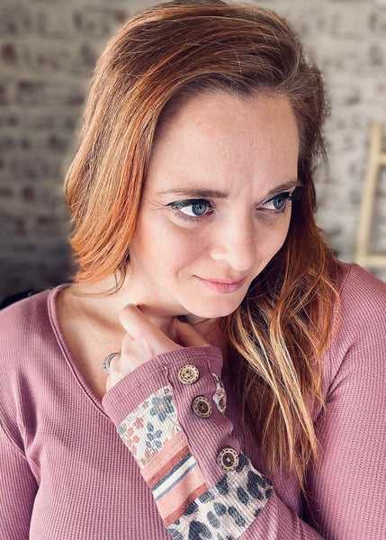 Woman wearing a pink waffle knit sweater with print and buttons on the cuff
